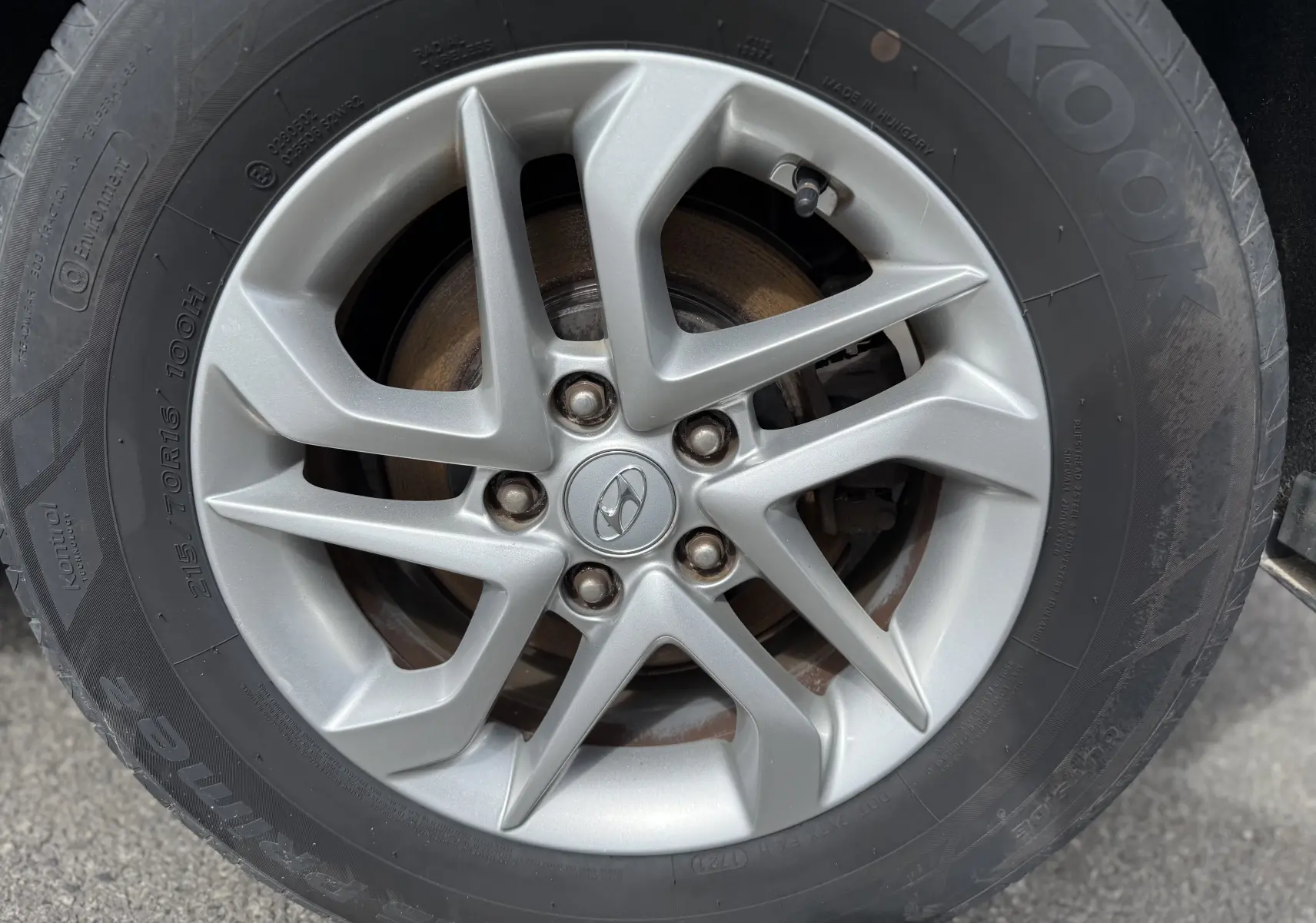 Gros plan sur la jante alliage argentée d'un Hyundai Tucson gris, mettant en valeur le logo Hyundai au centre.