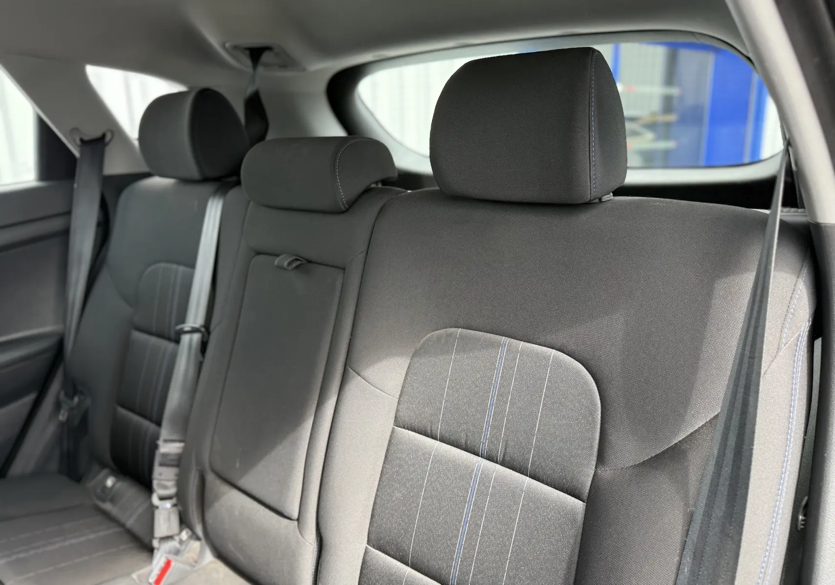 Vue rapprochée des sièges arrière en tissu gris foncé avec surpiqûres bleues du Hyundai Tucson 2015.