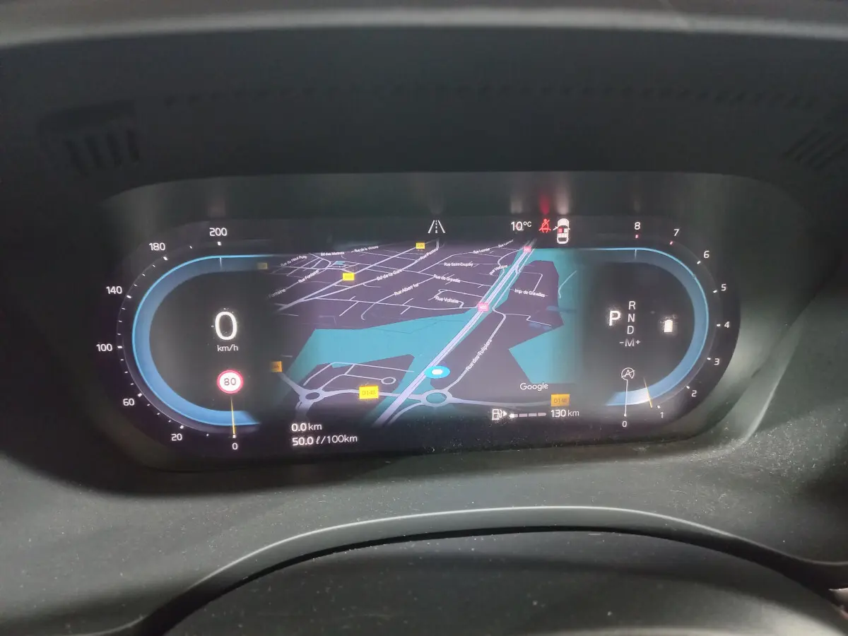 Affichage numérique du tableau de bord du Volvo XC60 gris clair, avec navigation et indicateurs de vitesse et mode.