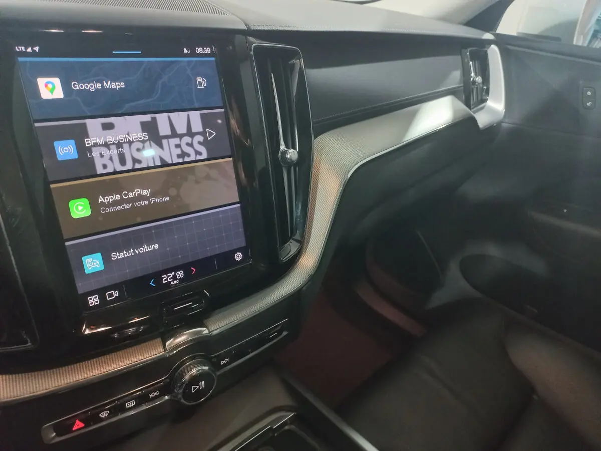 Vue intérieure côté passager du tableau de bord noir et écran tactile central affichant Google Maps dans un Volvo XC60 gris clair.