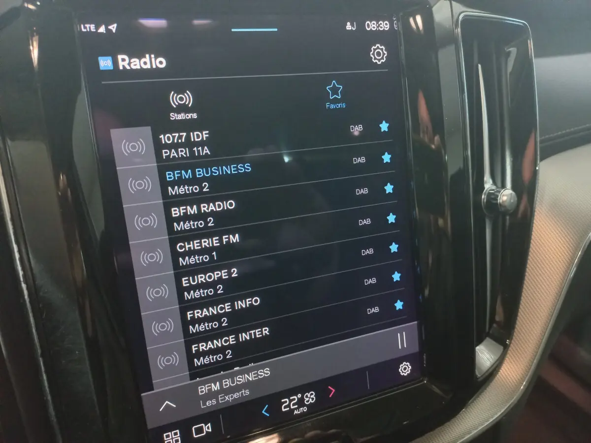Écran tactile central affichant les stations radio dans l’habitacle du Volvo XC60 gris clair, vue de côté droit.