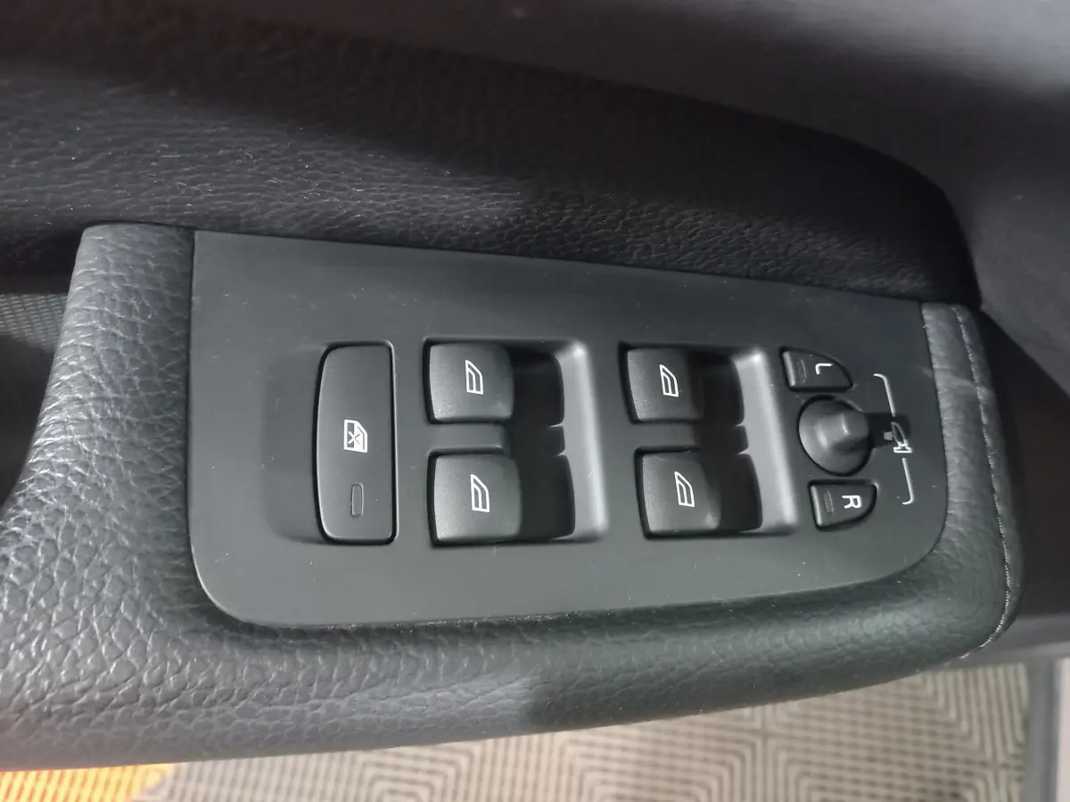 Commande des vitres et réglage des rétroviseurs sur la porte côté conducteur d'un Volvo XC60 gris clair 2022.