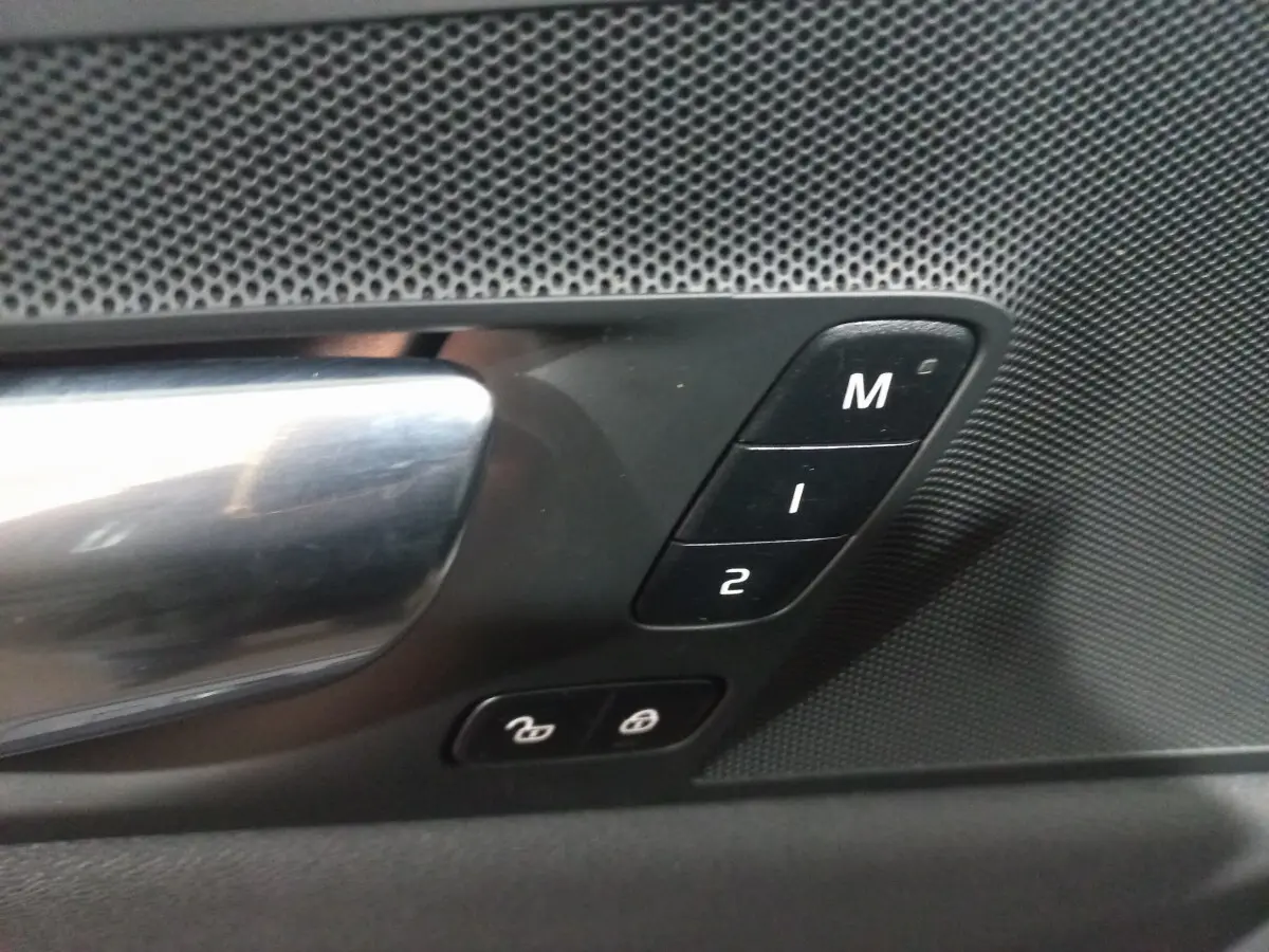 Gros plan sur la poignée intérieure côté gauche du Volvo XC60 gris clair avec boutons mémoire et verrouillage des portes.