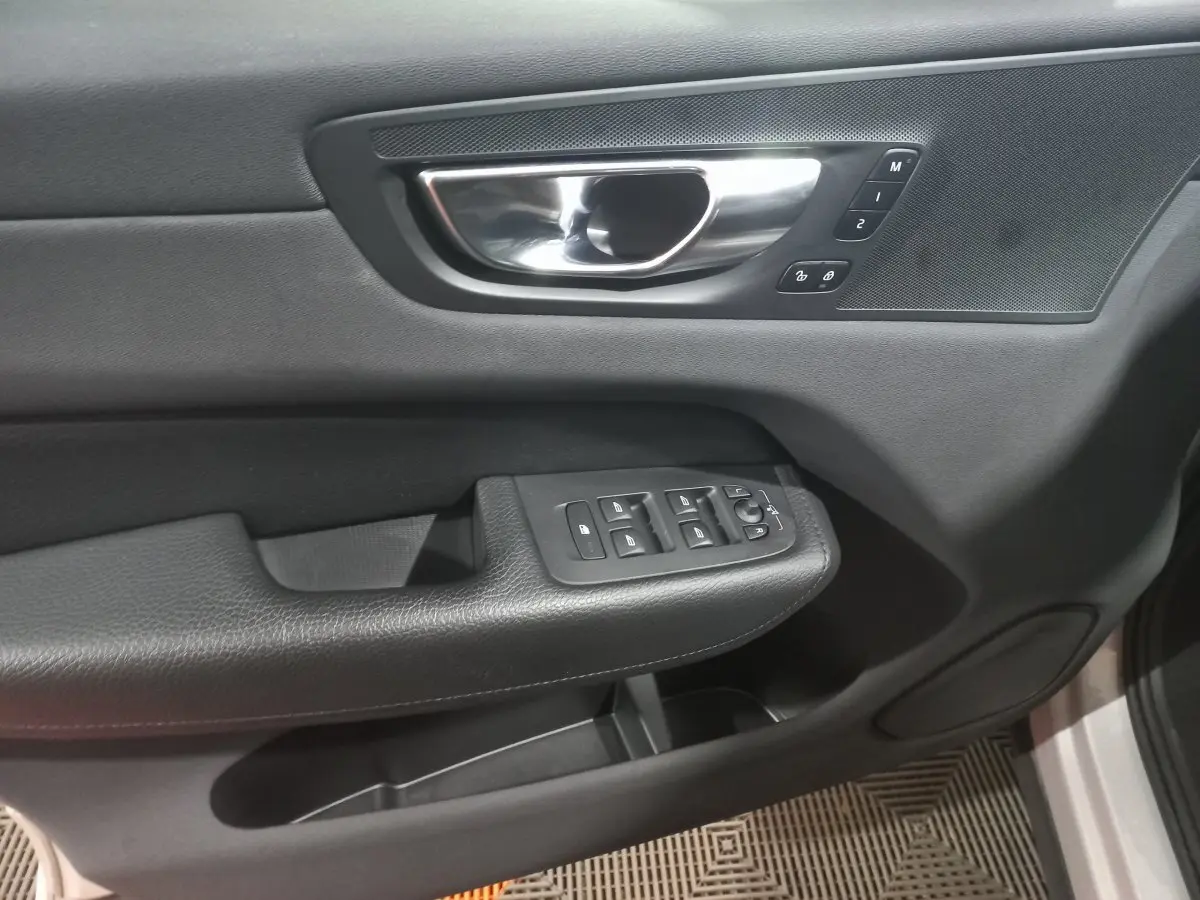 Poignée intérieure et commandes des vitres côté gauche en noir du Volvo XC60 B4 gris clair 2022.