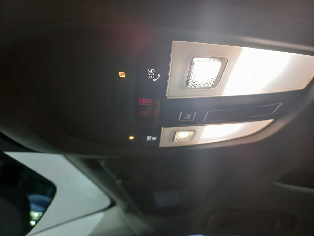 Plafonnier intérieur allumé avec commandes SOS et éclairage, vue du toit d'un Volvo XC60 gris clair 2022.