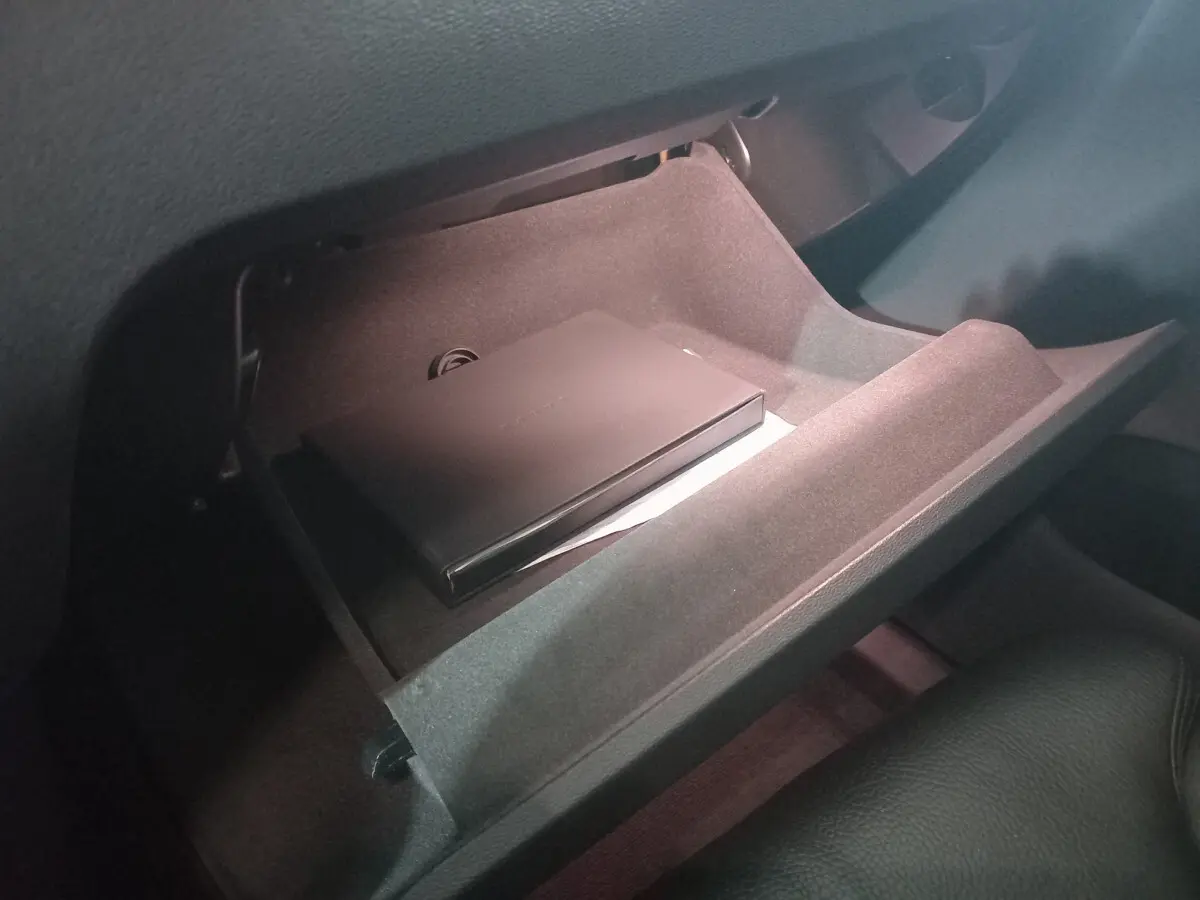 Gant de rangement ouvert côté passager du Volvo XC60 gris clair, montrant un boîtier noir à l'intérieur.