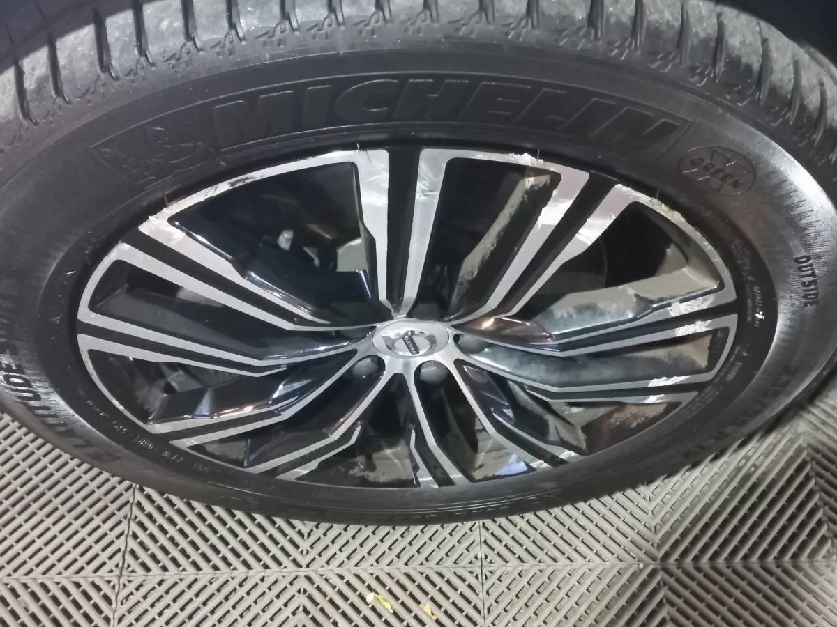 Gros plan sur la jante noire et argentée d'un Volvo XC60 B4 2022 avec pneu Michelin visible au sol.