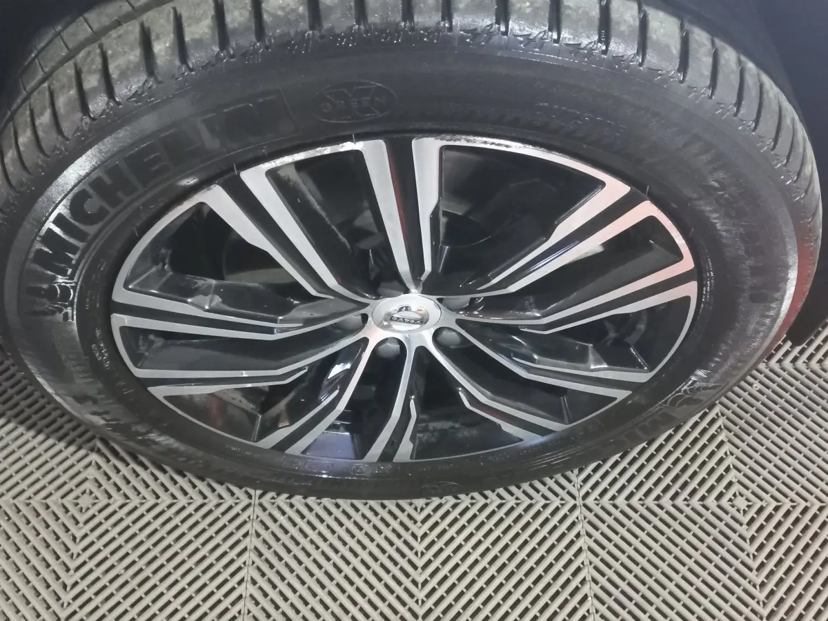 Gros plan sur la jante noire et argentée du Volvo XC60 B4 2022 avec pneu Michelin visible sur sol texturé.