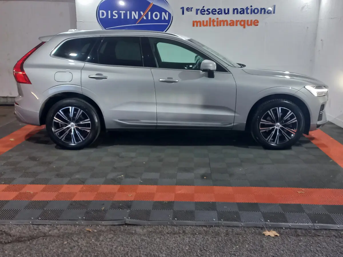 Profil côté droit d'un Volvo XC60 gris clair 2022 garé en intérieur avec jantes alliage et vitres teintées.