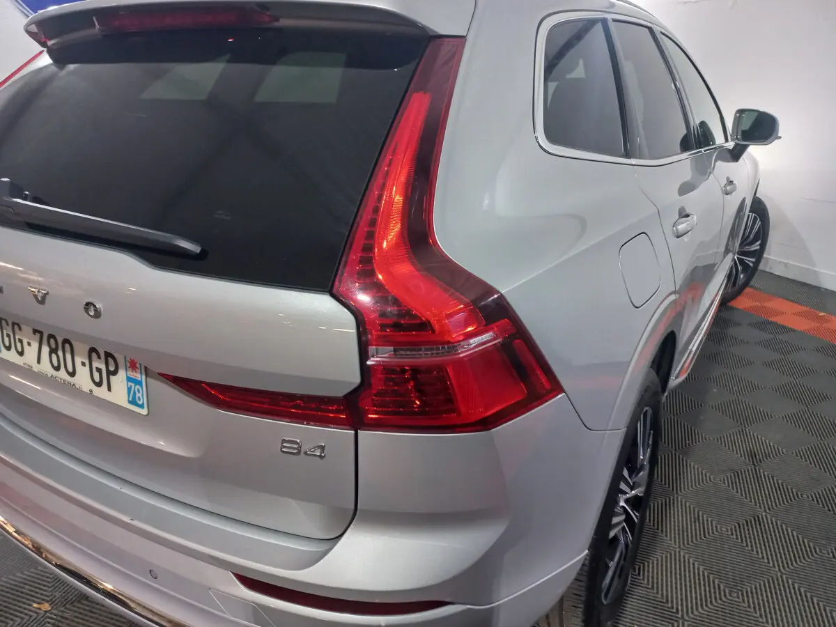 Vue 3/4 arrière droite d'un Volvo XC60 B4 gris clair avec feux arrière LED et jantes alliage noires.
