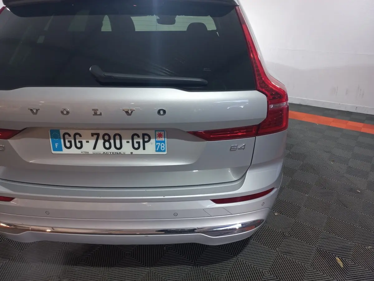 Vue arrière d'un Volvo XC60 B4 gris clair avec feux LED verticaux et plaque d'immatriculation française visible.
