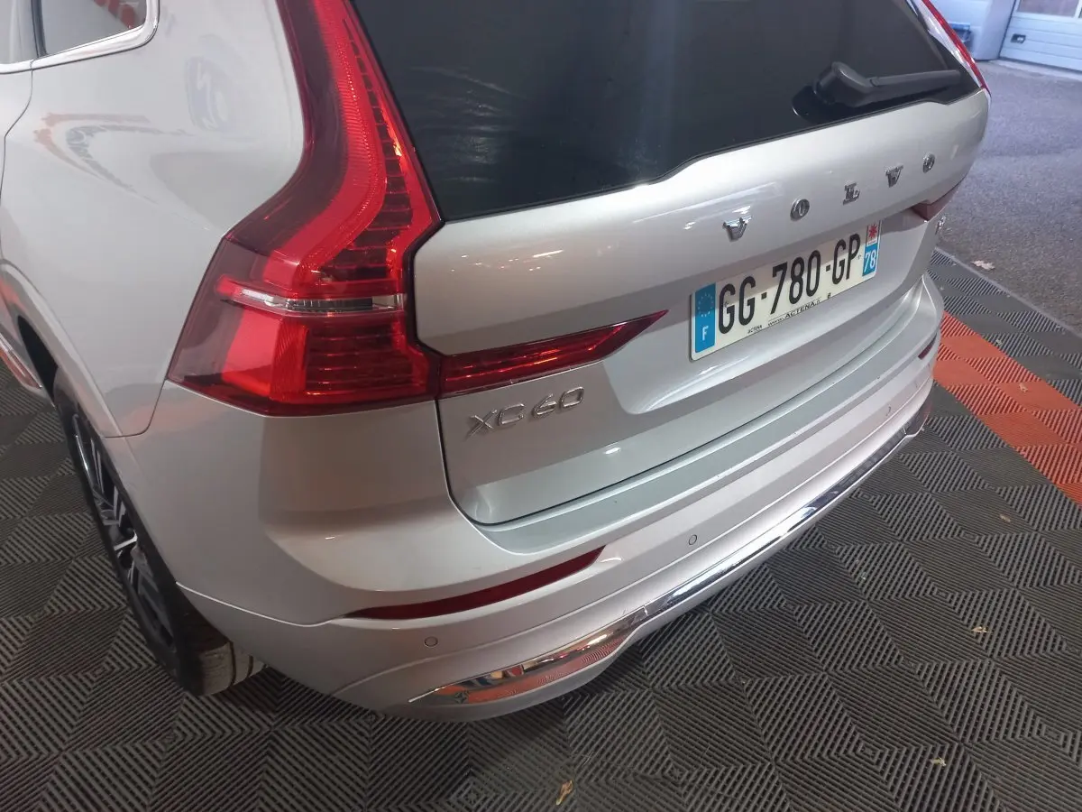 Vue 3/4 arrière droite du Volvo XC60 gris clair avec feux arrière LED et plaque d'immatriculation française visible.