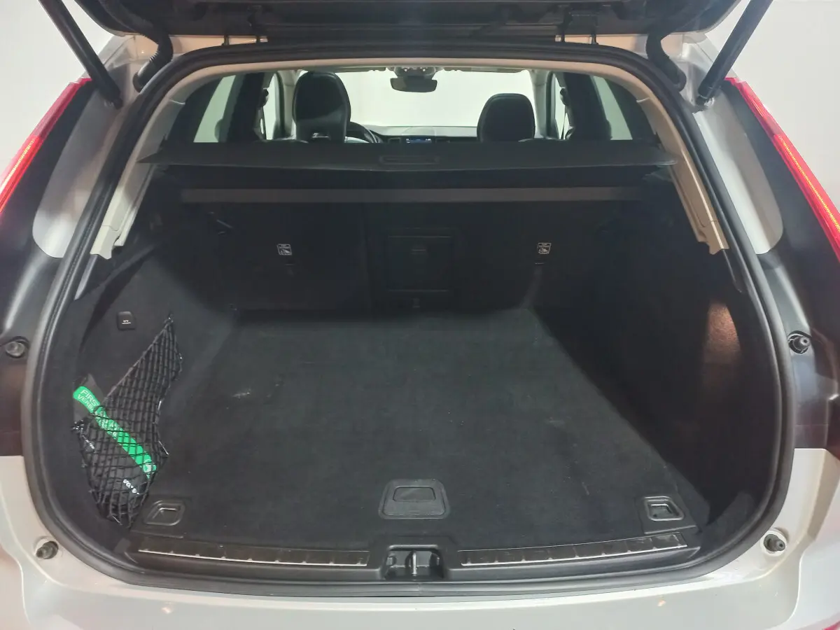 Coffre ouvert vu de l'arrière d'un Volvo XC60 gris clair, montrant l'espace de chargement et la tablette de séparation.