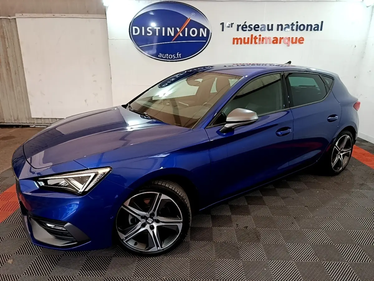 SEAT Leon 1.5 eTSI bleu en vue 3/4 avant droit, avec jantes alliage et rétroviseurs argentés dans un showroom.