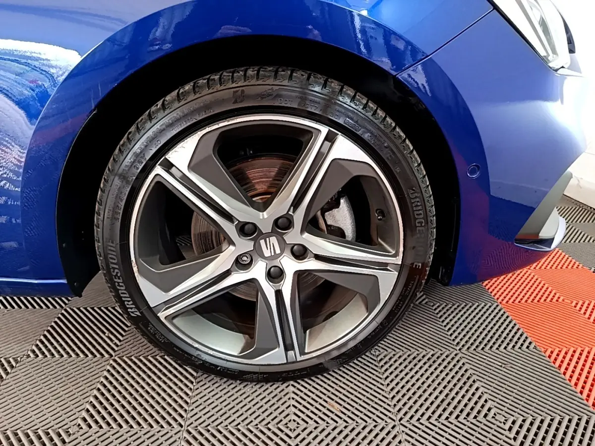 Gros plan sur la roue avant gauche d’une SEAT Leon bleu 2021 avec jante alliage à cinq branches.
