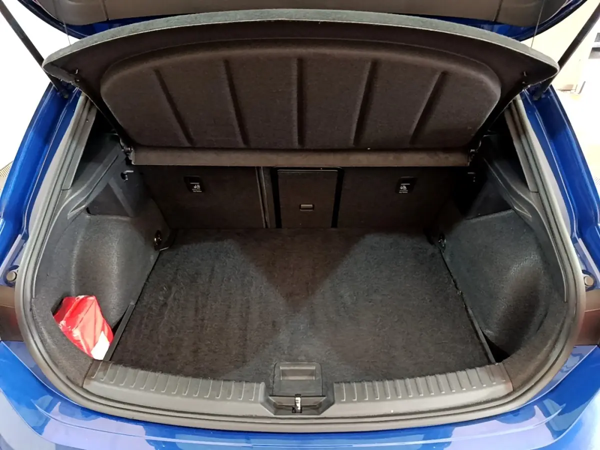 Coffre ouvert d'une SEAT LEON bleu 2021, vue arrière montrant un espace de rangement propre et un kit de secours rouge.