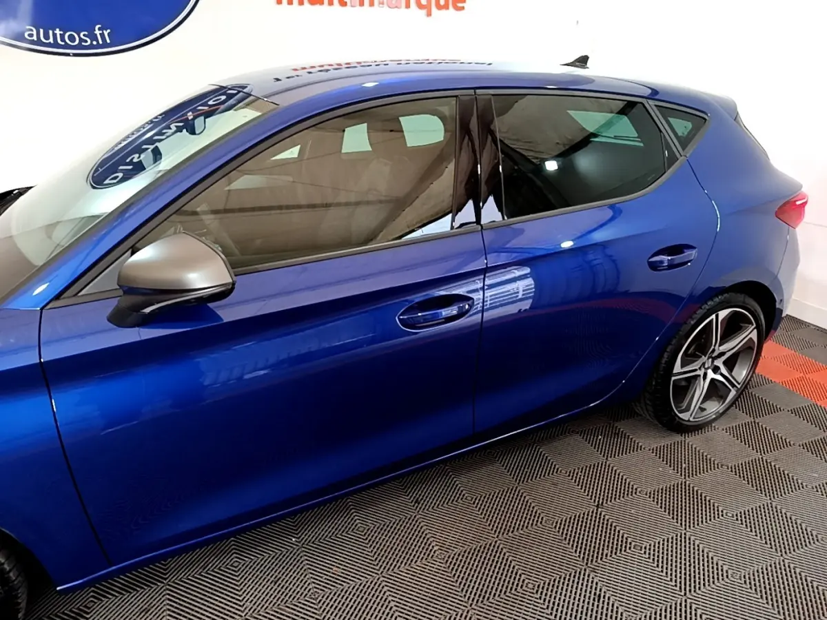 Vue latérale gauche d'une SEAT Leon bleu métallisé avec rétroviseur argent et jantes alliage sport.