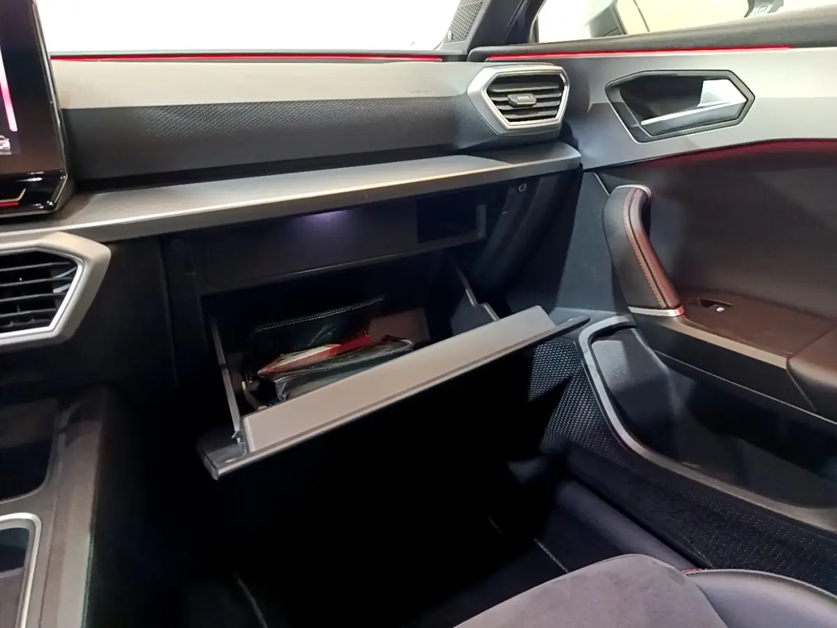 Intérieur SEAT Leon 1.5 eTSI 2021, vue côté passager sur boîte à gants ouverte et détails du tableau de bord noir.