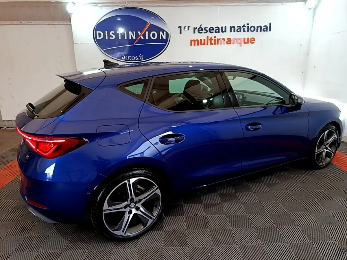 Vue latérale droite d'une SEAT Leon 1.5 eTSI bleu 2021 avec jantes alliage et feux arrière LED allumés.