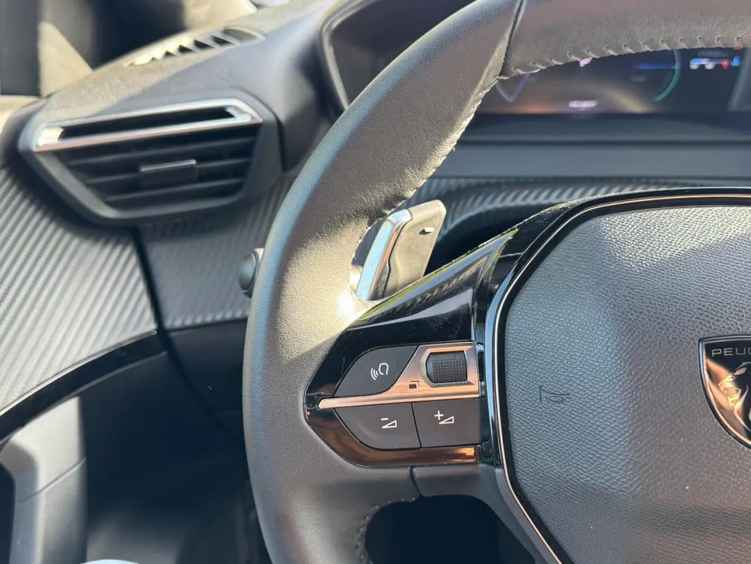 Gros plan sur le volant noir du Peugeot 2008 Hybrid 136 e-DCS6 Allure avec commandes intégrées et tableau de bord partiellement visible.