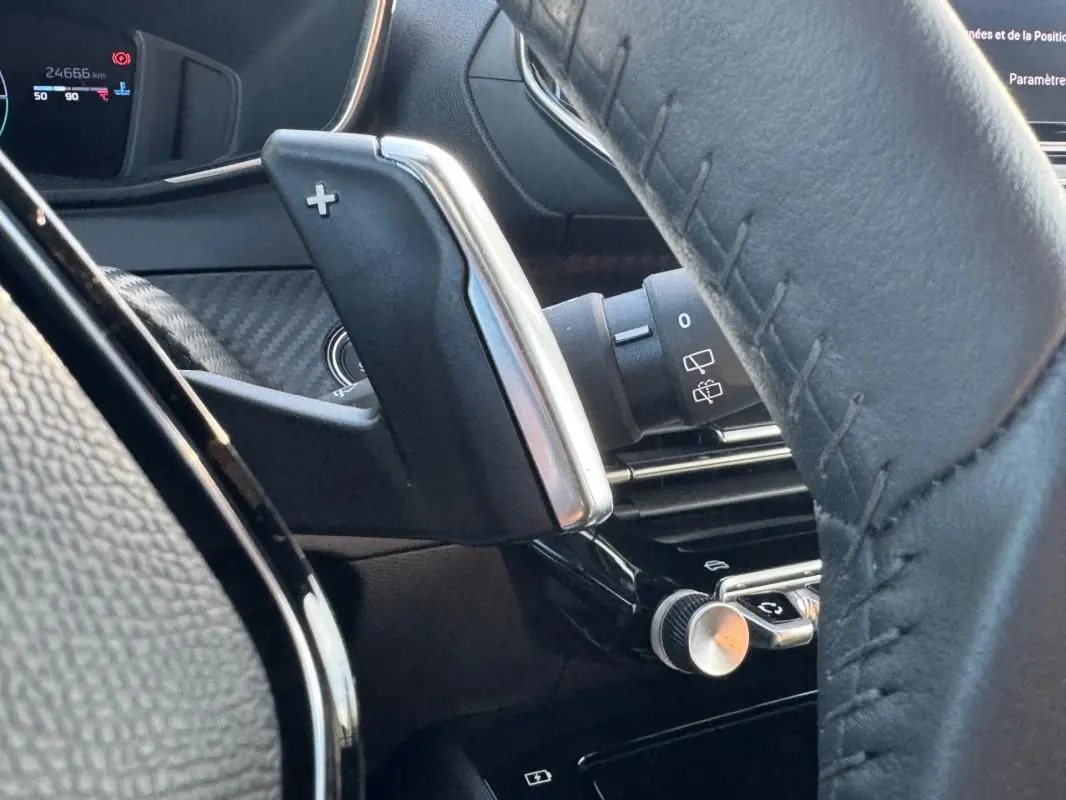 Détail intérieur du Peugeot 2008 Hybrid 136 e-DCS6 Allure 2025, montrant la palette de changement de vitesse côté gauche du volant noir.