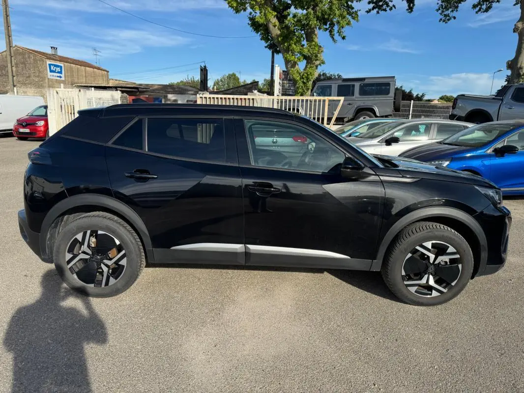 Peugeot 2008 Hybrid noir vue de profil côté gauche, avec jantes alliage 17 pouces et barres de toit visibles.