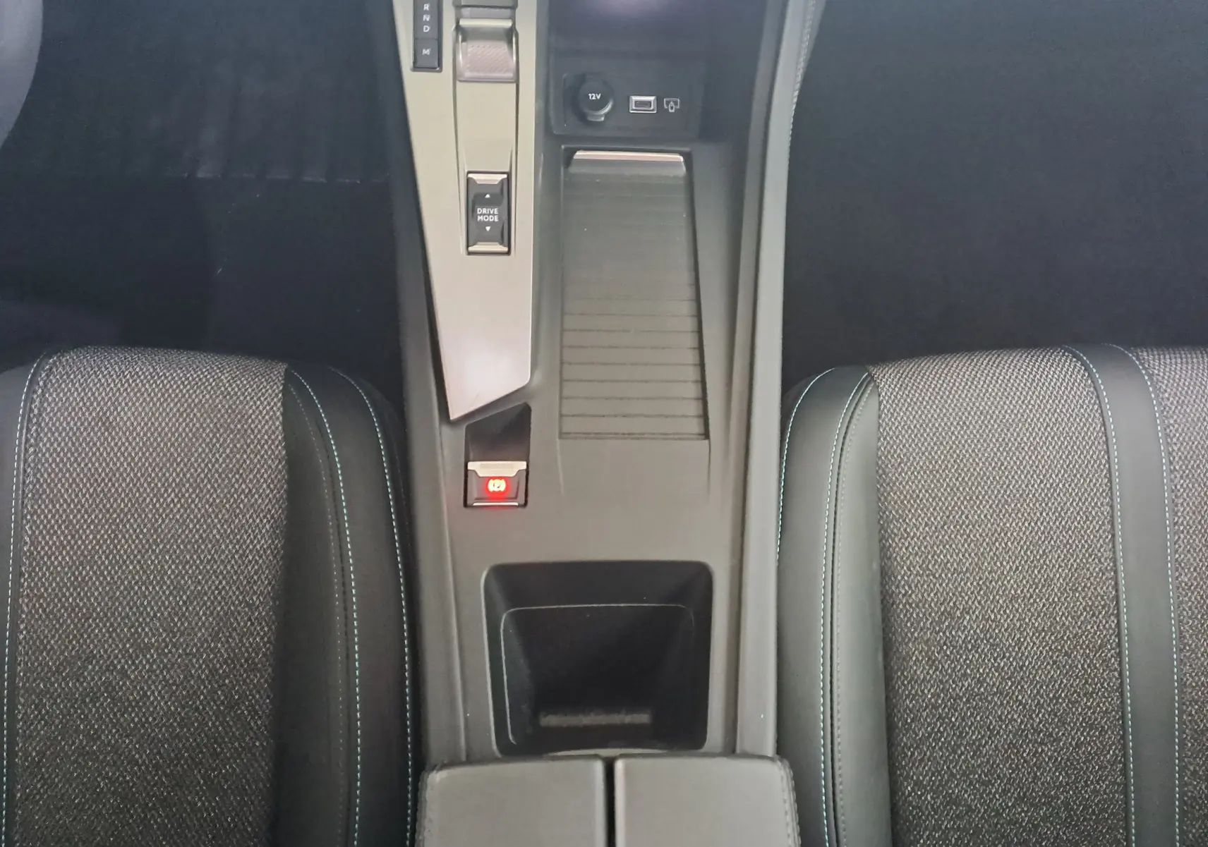 Vue plongeante sur la console centrale et les sièges gris foncé avec surpiqûres bleues de la Peugeot 308 2023.