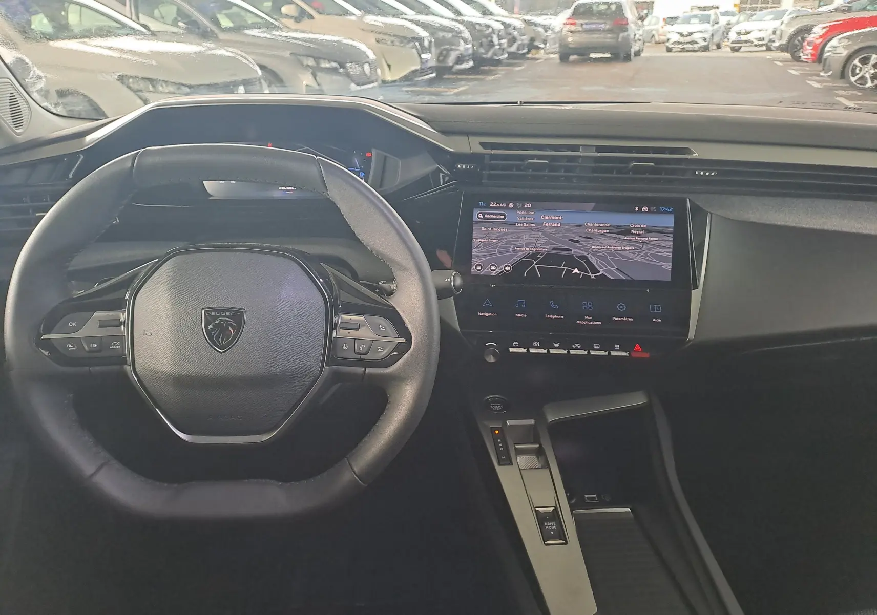 Vue intérieure du poste de conduite de la Peugeot 308 2023 avec volant compact et écran tactile central affichant la navigation.