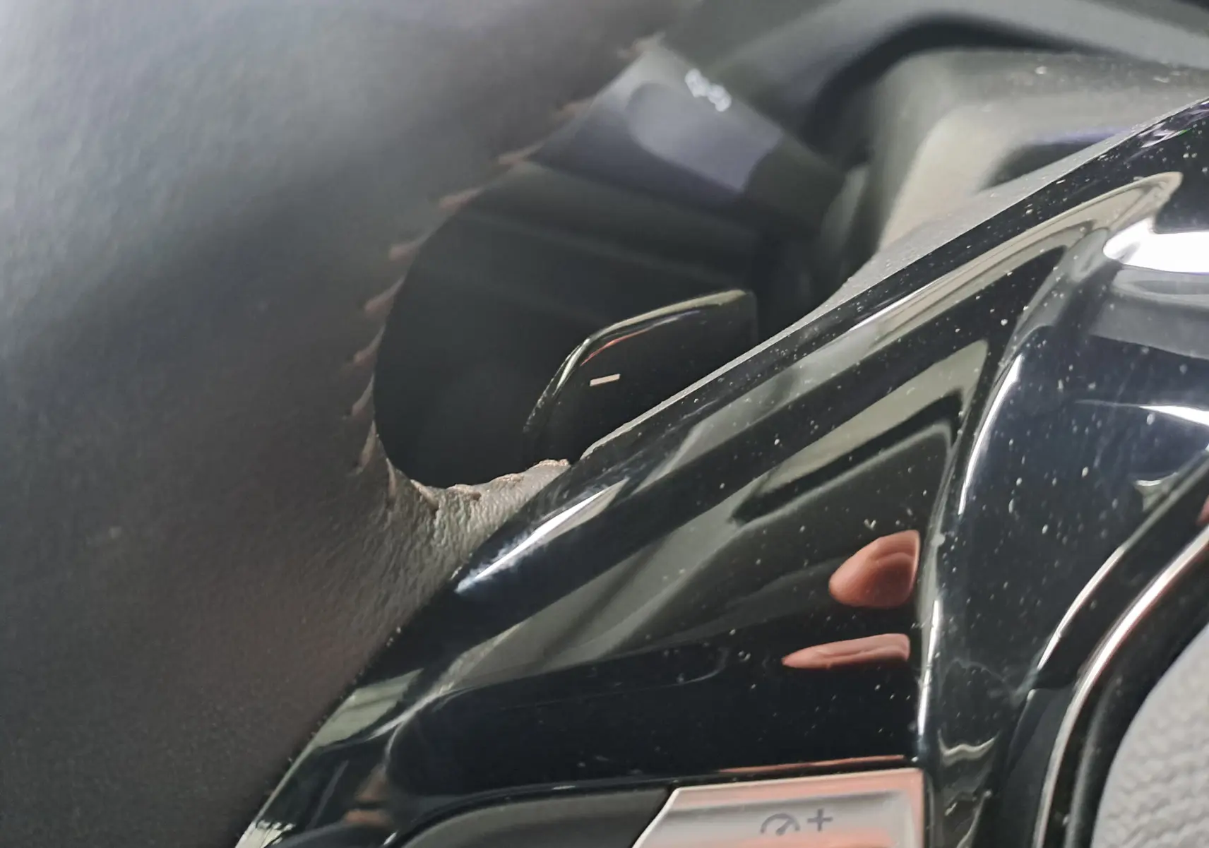 Gros plan sur la commande de régulateur de vitesse au volant noir brillant d'une Peugeot 308 gris Artense 2023.