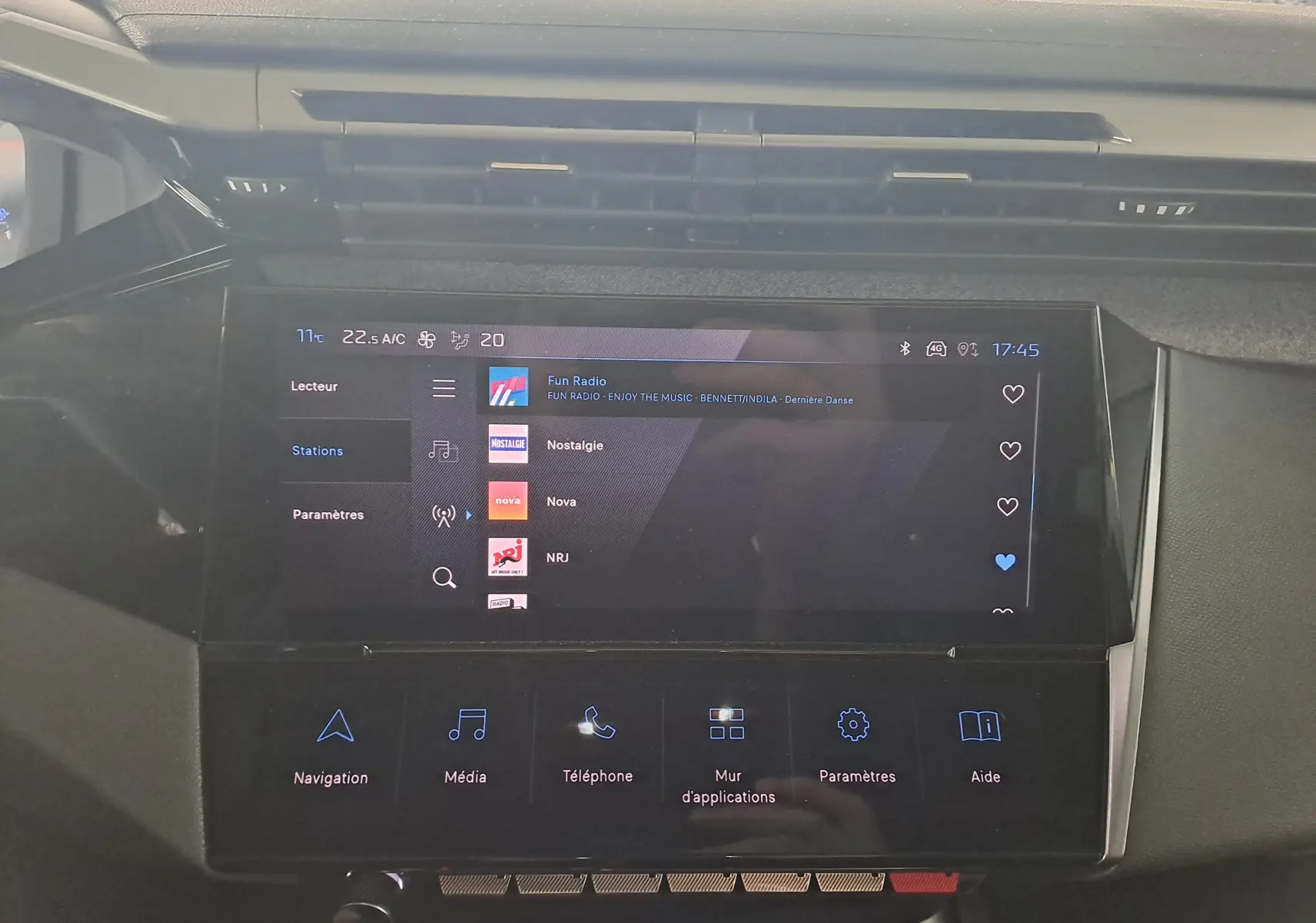 Écran tactile central du tableau de bord de la Peugeot 308 gris Artense, affichant les stations radio et options multimédia.