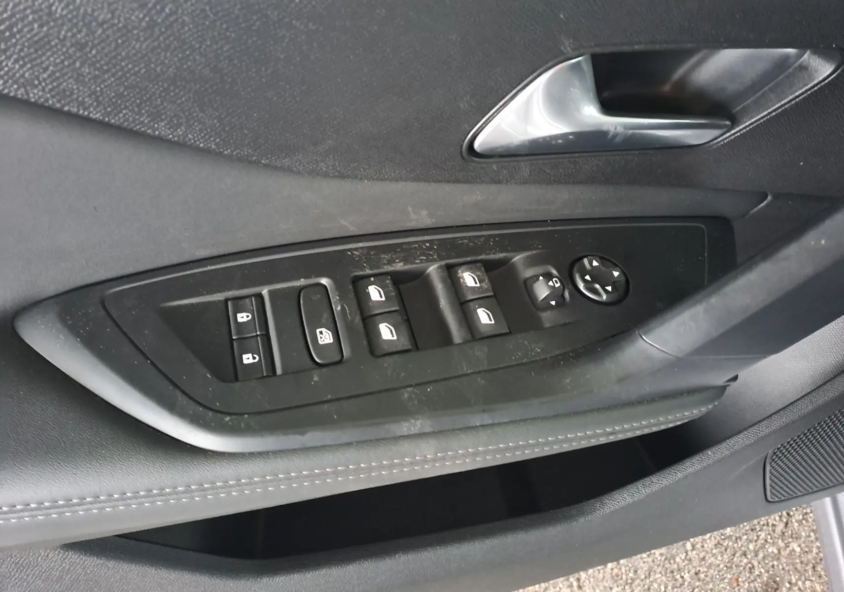 Gros plan sur la commande des vitres et rétroviseurs côté gauche de la porte d'une Peugeot 308 gris Artense 2023.
