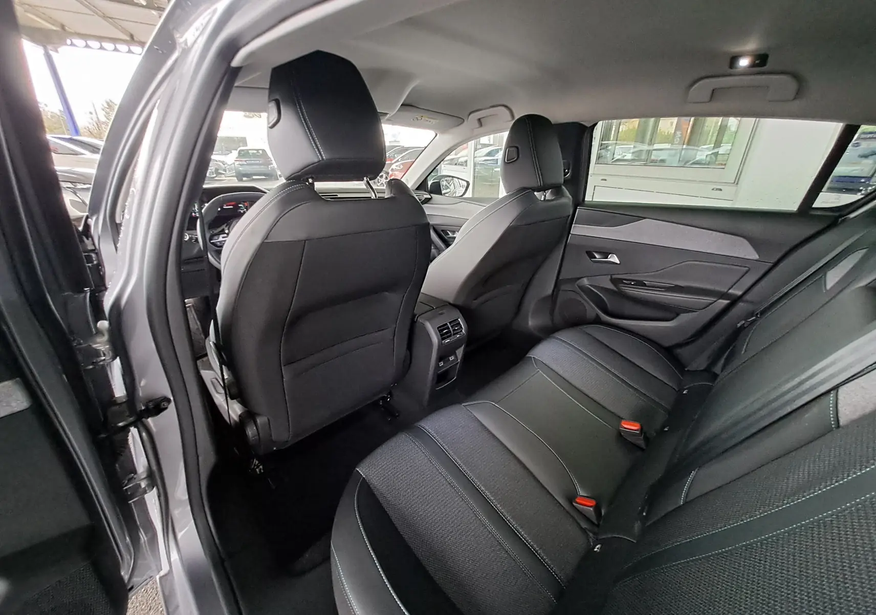 Vue intérieure arrière gauche de la Peugeot 308 gris Artense 2023, montrant les sièges arrière et la console centrale.