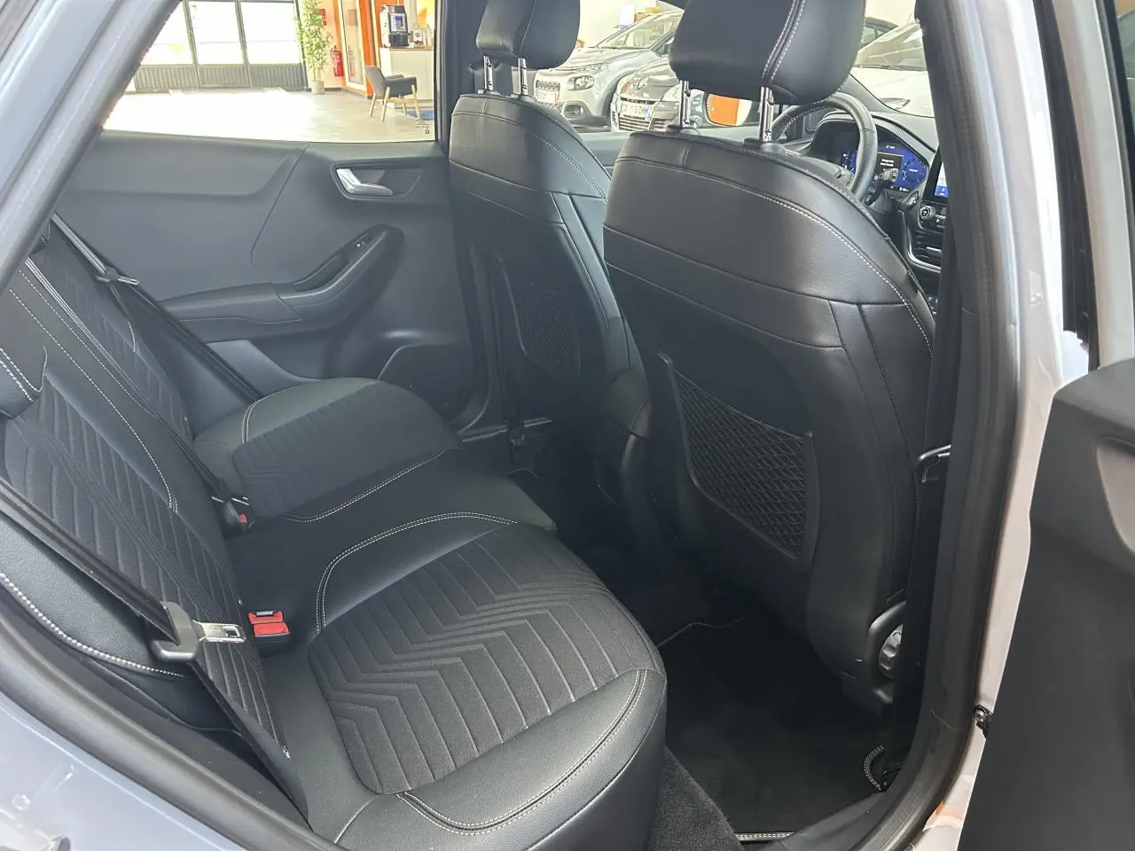 Vue intérieure arrière côté gauche du Ford Puma gris, montrant les sièges arrière en tissu et cuir noir avec surpiqûres blanches.