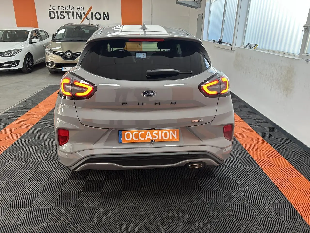 Vue arrière d'un Ford Puma gris métallisé avec feux arrière LED allumés dans un showroom.