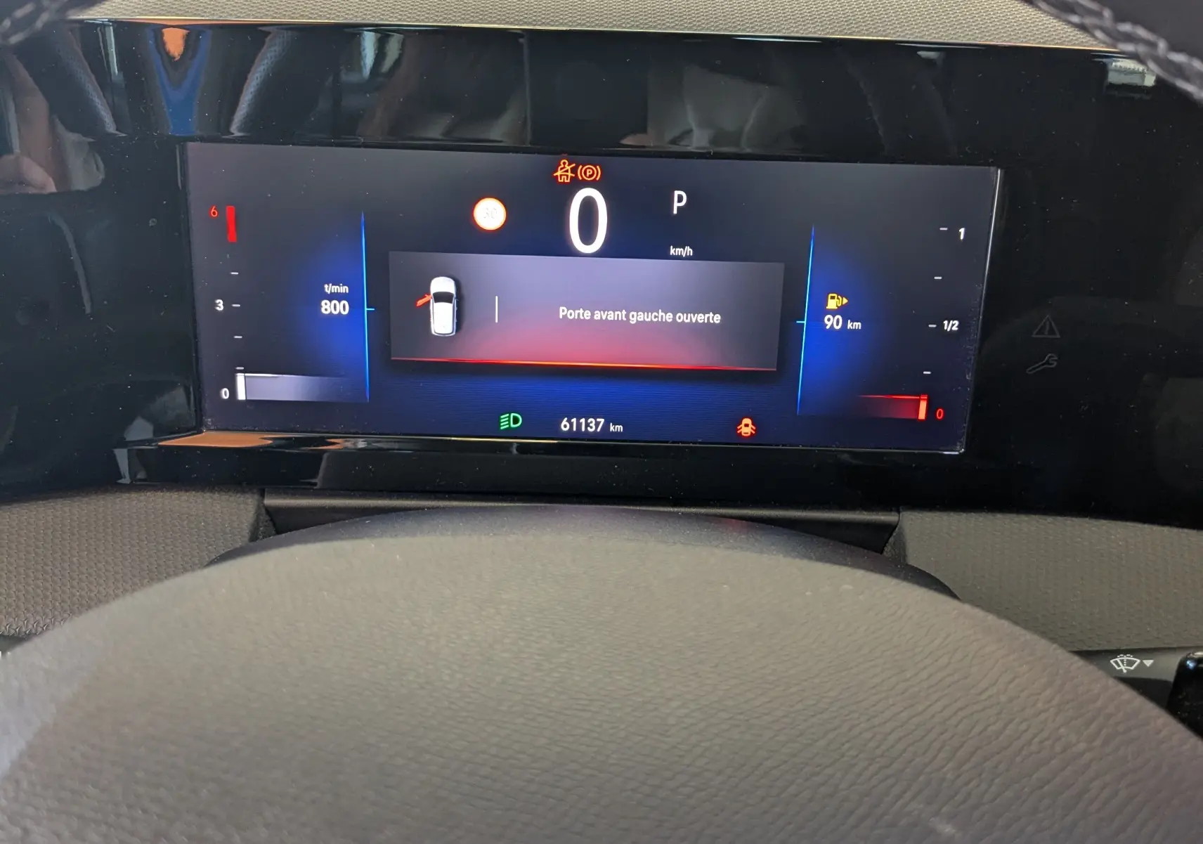 Vue rapprochée du tableau de bord numérique de l'Opel Astra bleu, affichant une porte avant gauche ouverte.