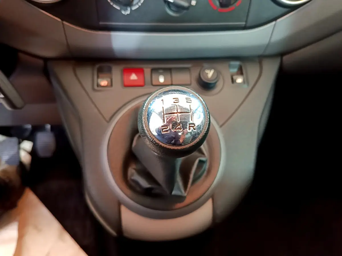 Gros plan sur le levier de vitesse manuel du Citroën Berlingo BlueHDi 75, entouré de commandes sur console grise.
