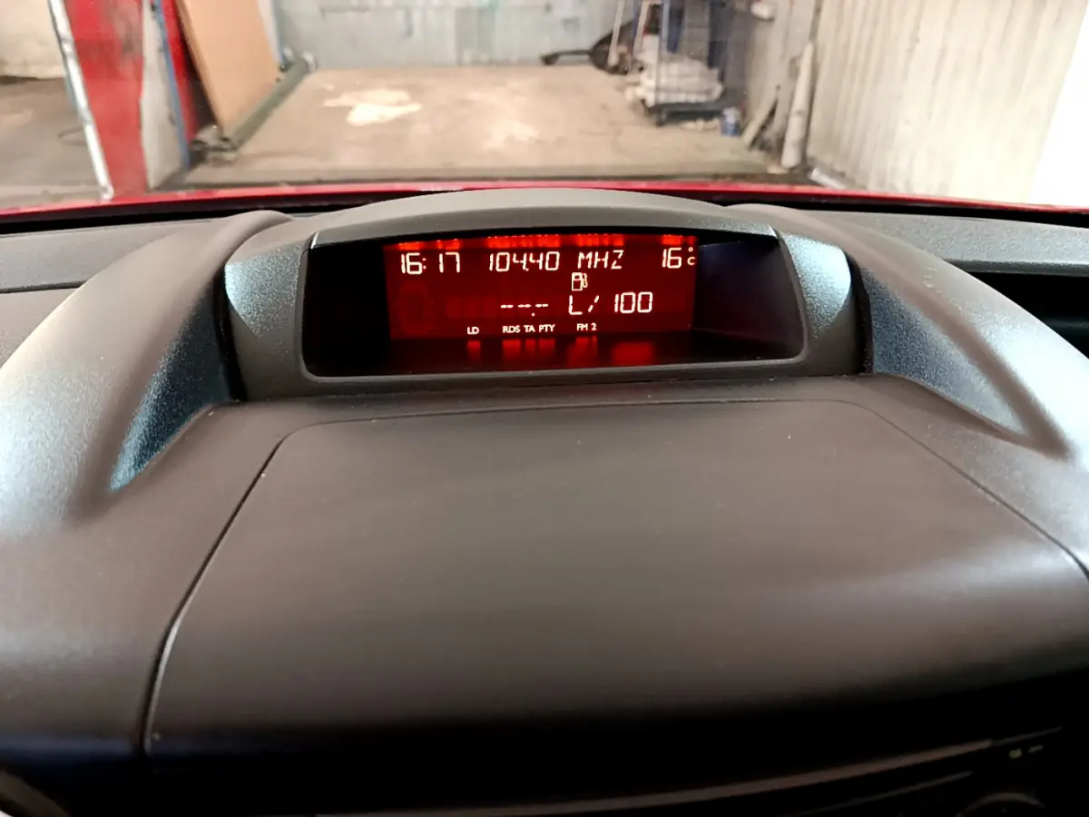 Affichage central du tableau de bord du Citroën Berlingo rouge, avec écran numérique rouge montrant l'heure et la température.