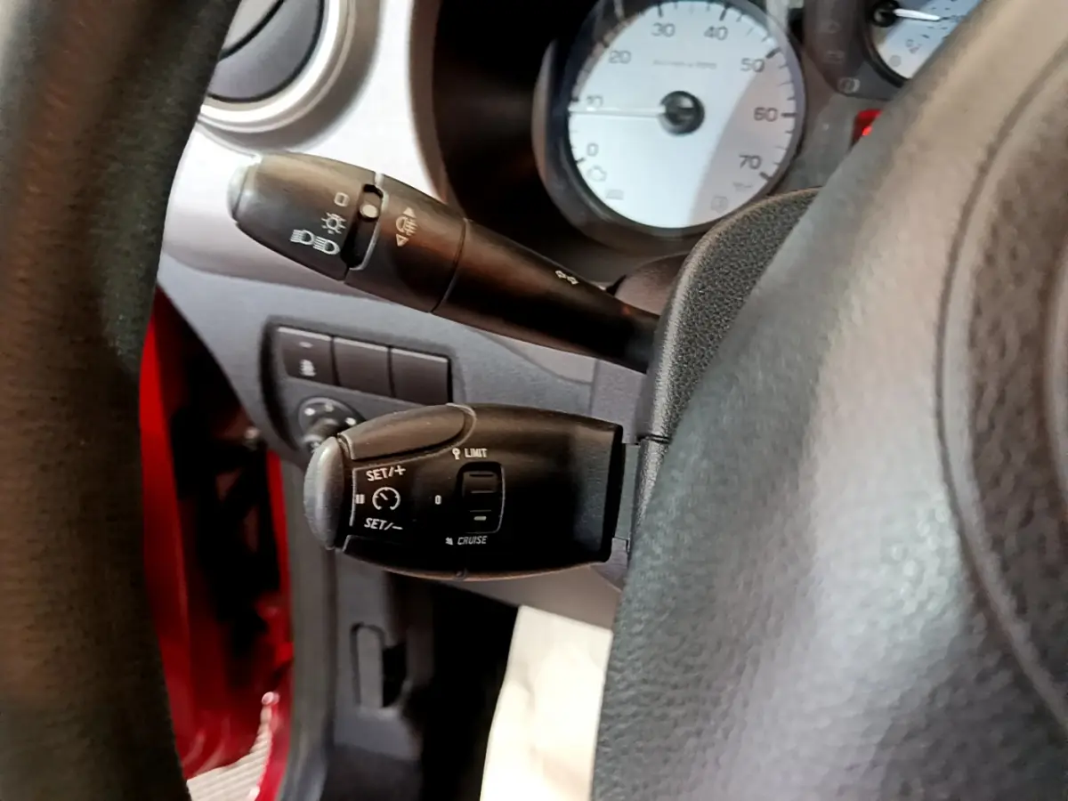 Gros plan sur les commandes de régulateur de vitesse et feux du tableau de bord du Citroën Berlingo rouge côté conducteur.