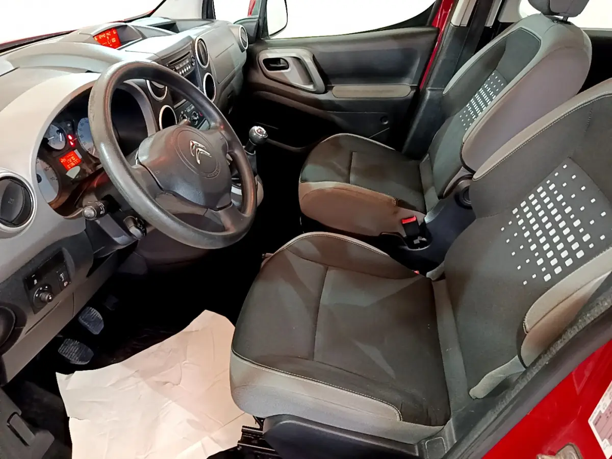 Vue intérieure côté conducteur du Citroën Berlingo rouge 2016, montrant sièges noirs et tableau de bord gris.