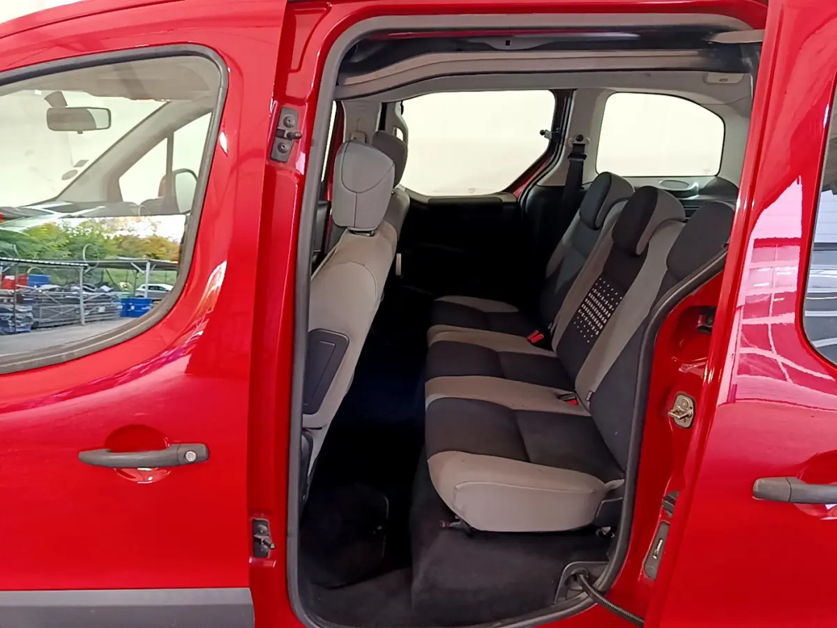 Vue latérale gauche du Citroën Berlingo rouge 2016 avec porte coulissante ouverte sur la banquette arrière trois places.