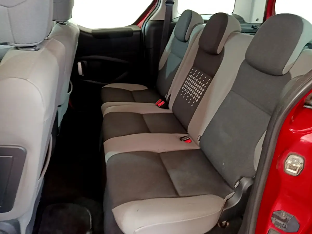 Vue intérieure sur la banquette arrière grise et noire du Citroën Berlingo rouge, porte arrière ouverte côté droit.