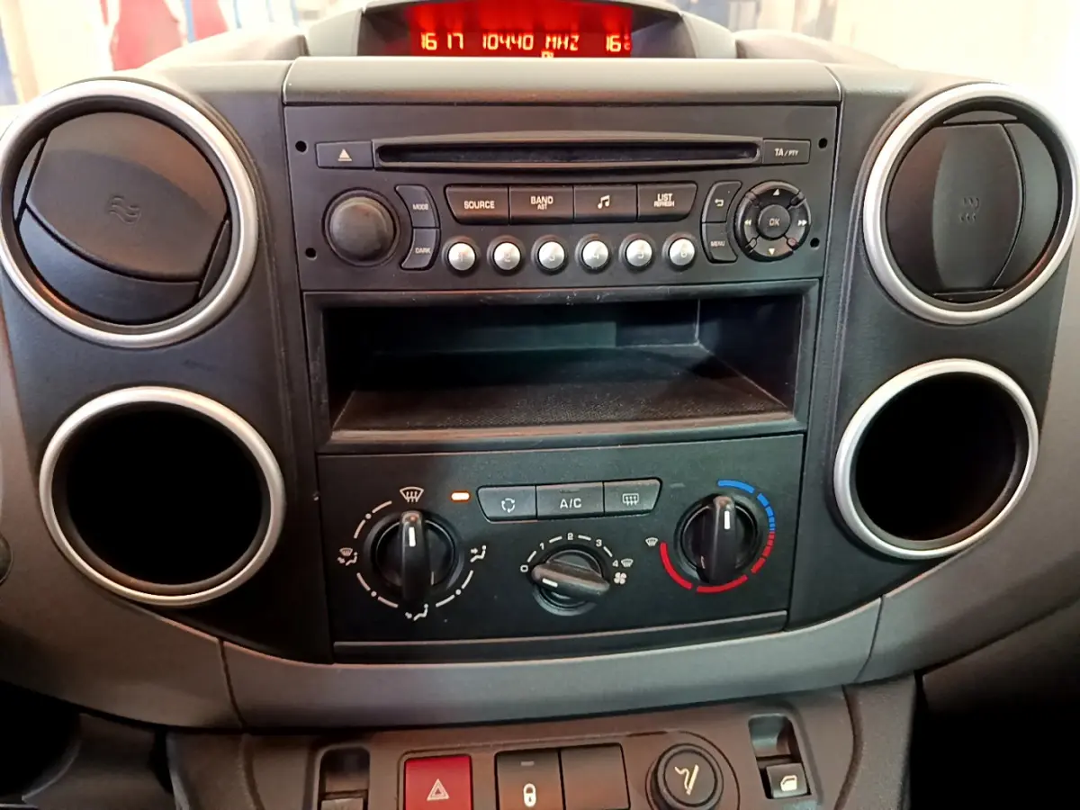 Tableau de bord central du Citroën Berlingo 2016, vue frontale montrant la radio, commandes de climatisation et aérateurs ronds noirs.