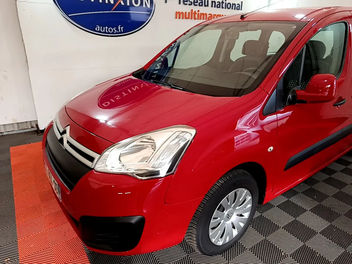 Vue 3/4 avant droit d'un Citroën Berlingo rouge avec phares halogènes et protections latérales noires.