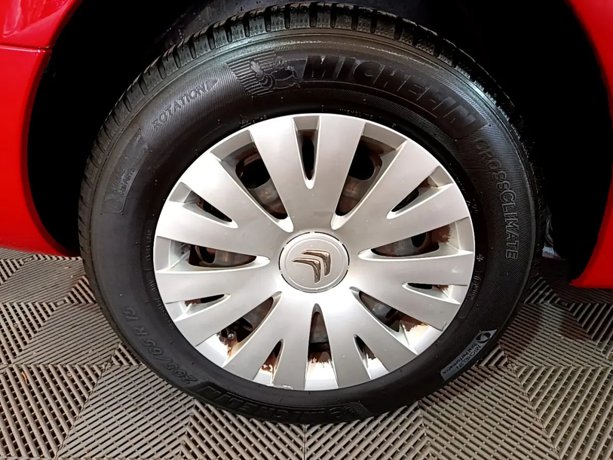 Gros plan sur la roue avant gauche rouge d'un Citroën Berlingo 2016 avec jante en enjoliveur argenté.