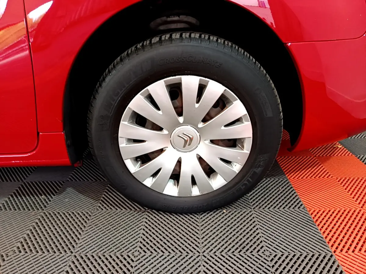 Gros plan sur la roue avant gauche rouge d’un Citroën Berlingo avec enjoliveur argenté et pneu Michelin.