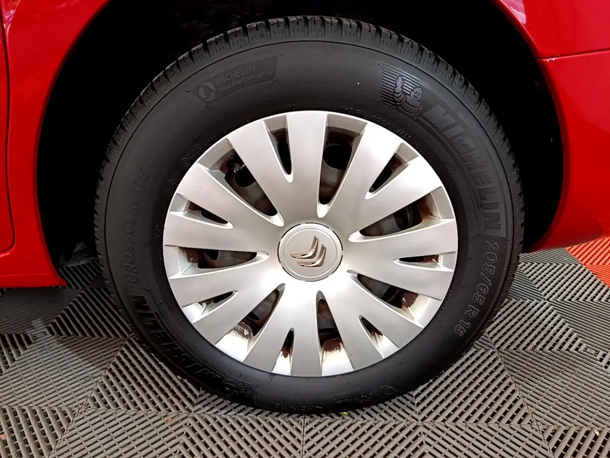 Gros plan sur la roue avant droite rouge d'une Citroën Berlingo 2016 avec enjoliveur argenté et pneu Michelin.