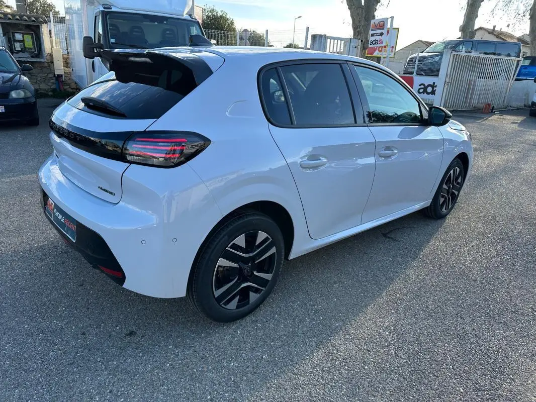 Vue 3/4 arrière droite d’une Peugeot 208 Hybrid 110 blanche avec jantes alliage noires et toit noir brillant.