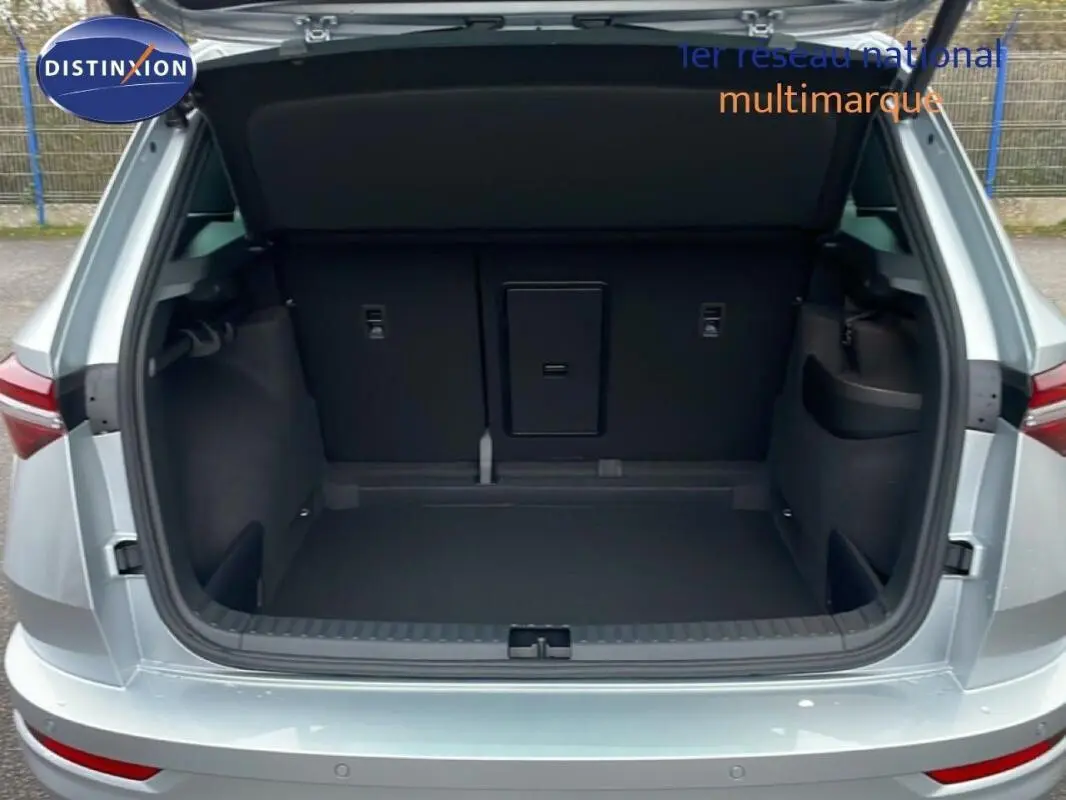 Coffre ouvert vu de l'arrière d'un Skoda Karoq argent 2025, avec intérieur de coffre spacieux et banquette rabattable.