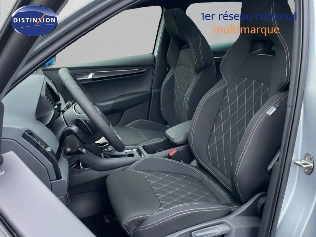 Vue intérieure côté gauche du Skoda Karoq argent 2025, sièges sport noirs avec surpiqûres blanches et volant multifonctions.