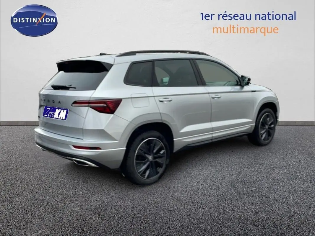 Vue 3/4 arrière droite d'un Skoda Karoq argent avec barres de toit et vitres arrière teintées.